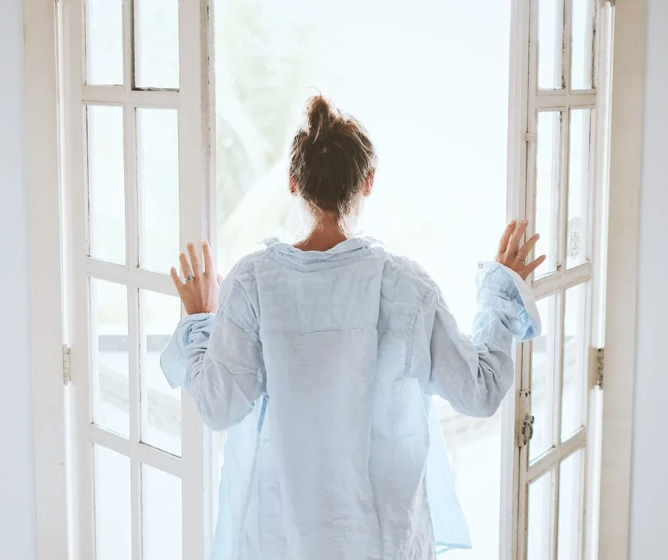 rytm okołodobowy kobieta o poranku w drzwiach balkonowych